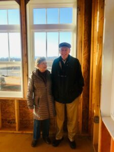 A senior couple smile for a picture in a new senior living cottage under construction at The Culpeper.