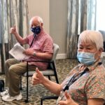 Residents give a thumbs-up while waiting for covid vaccines.