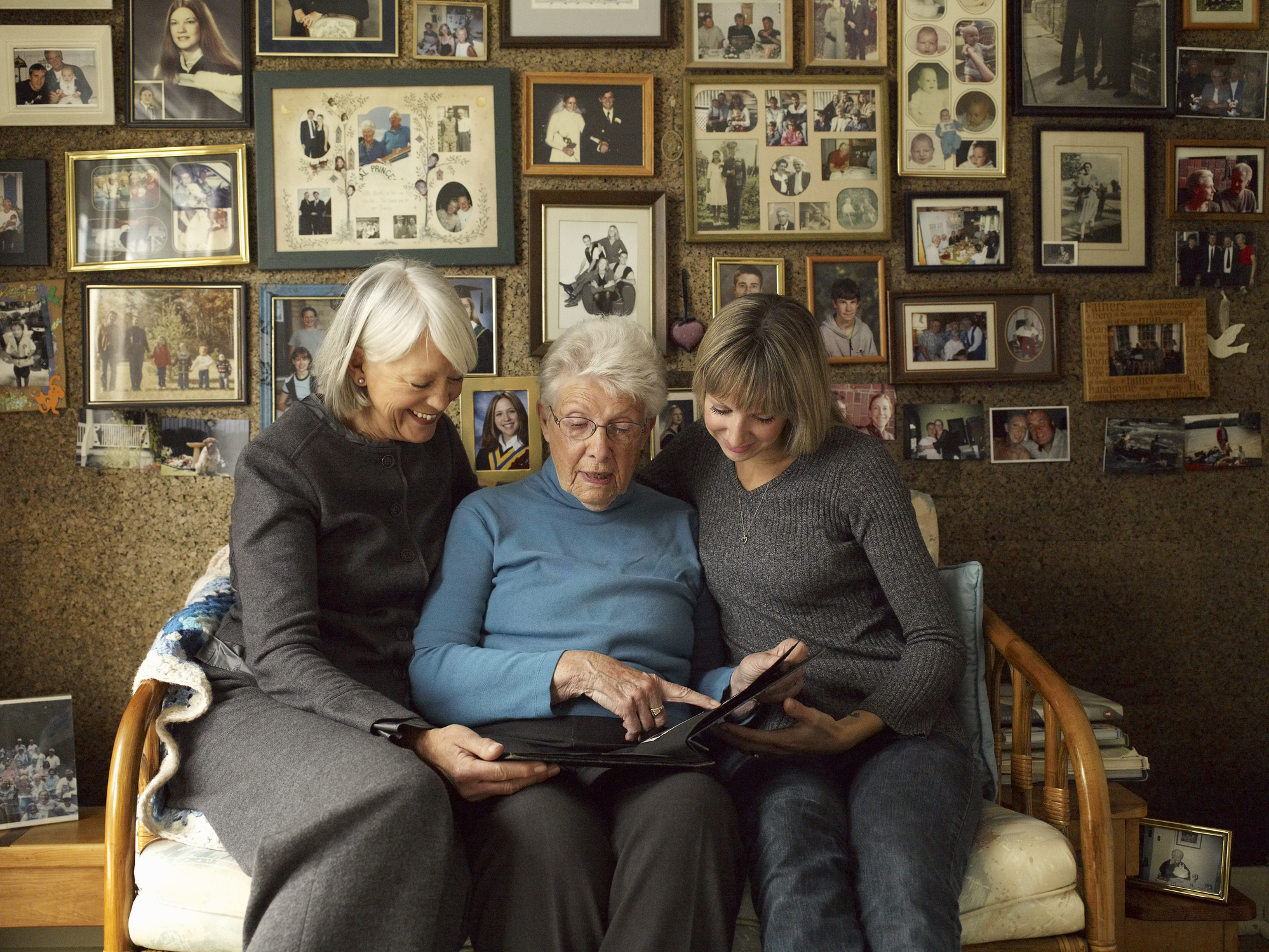 Three older women look at family photos together