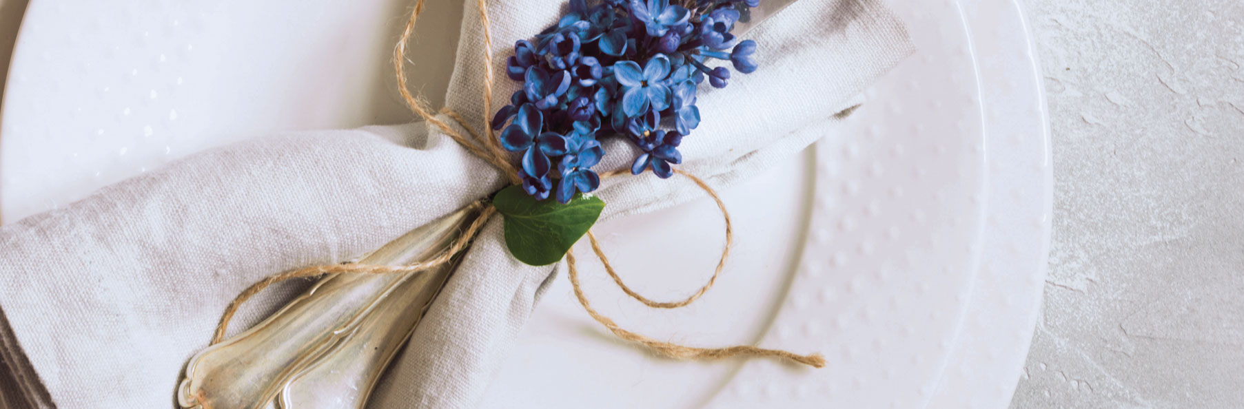 A close up photo of a plate with silverware napkin and flower