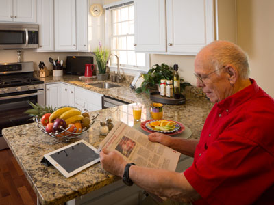 A senior man reads the newspaper at his senior living home
